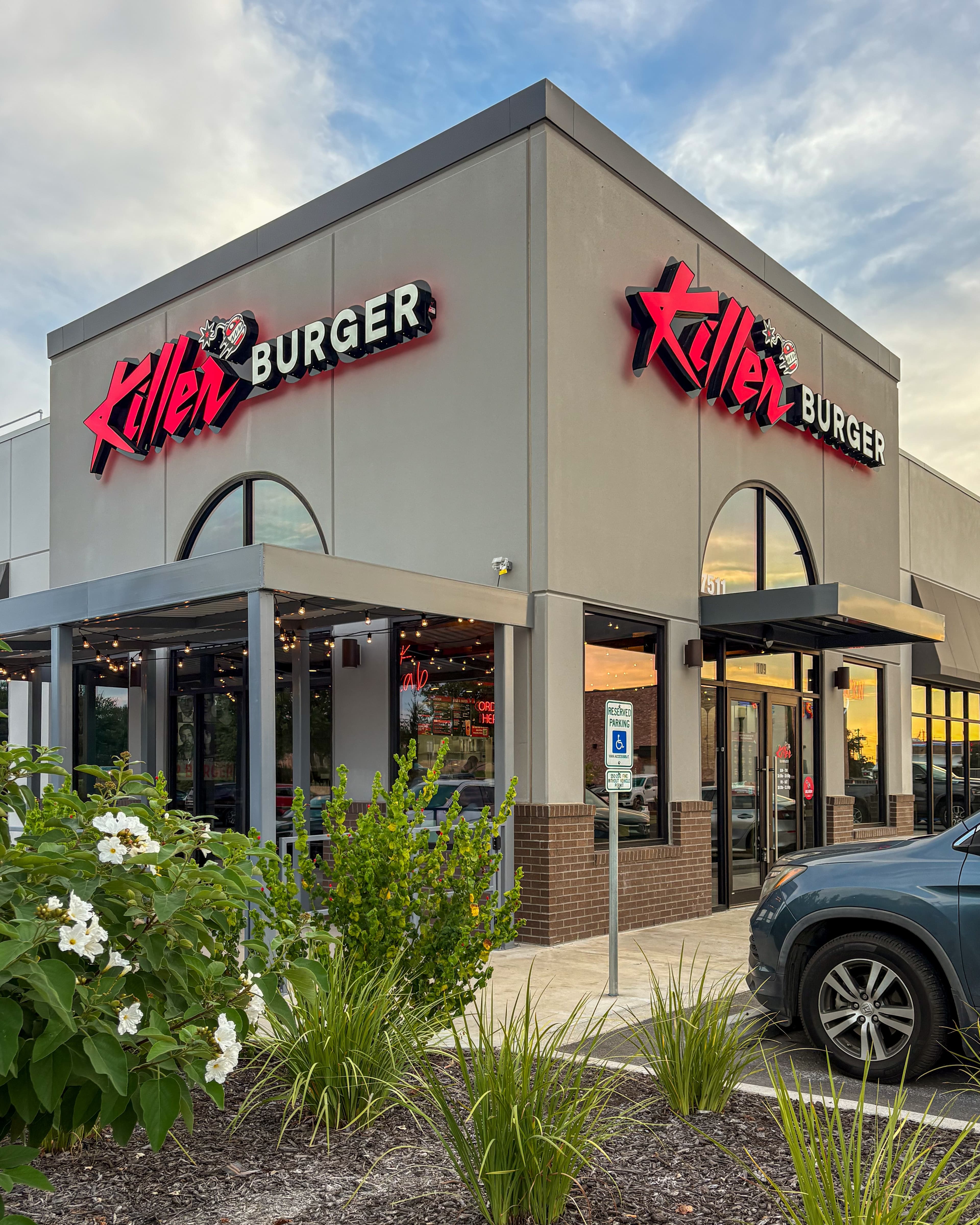 Killer Burger Brooks — exterior corner storefront at dusk with landscaping and lit signage