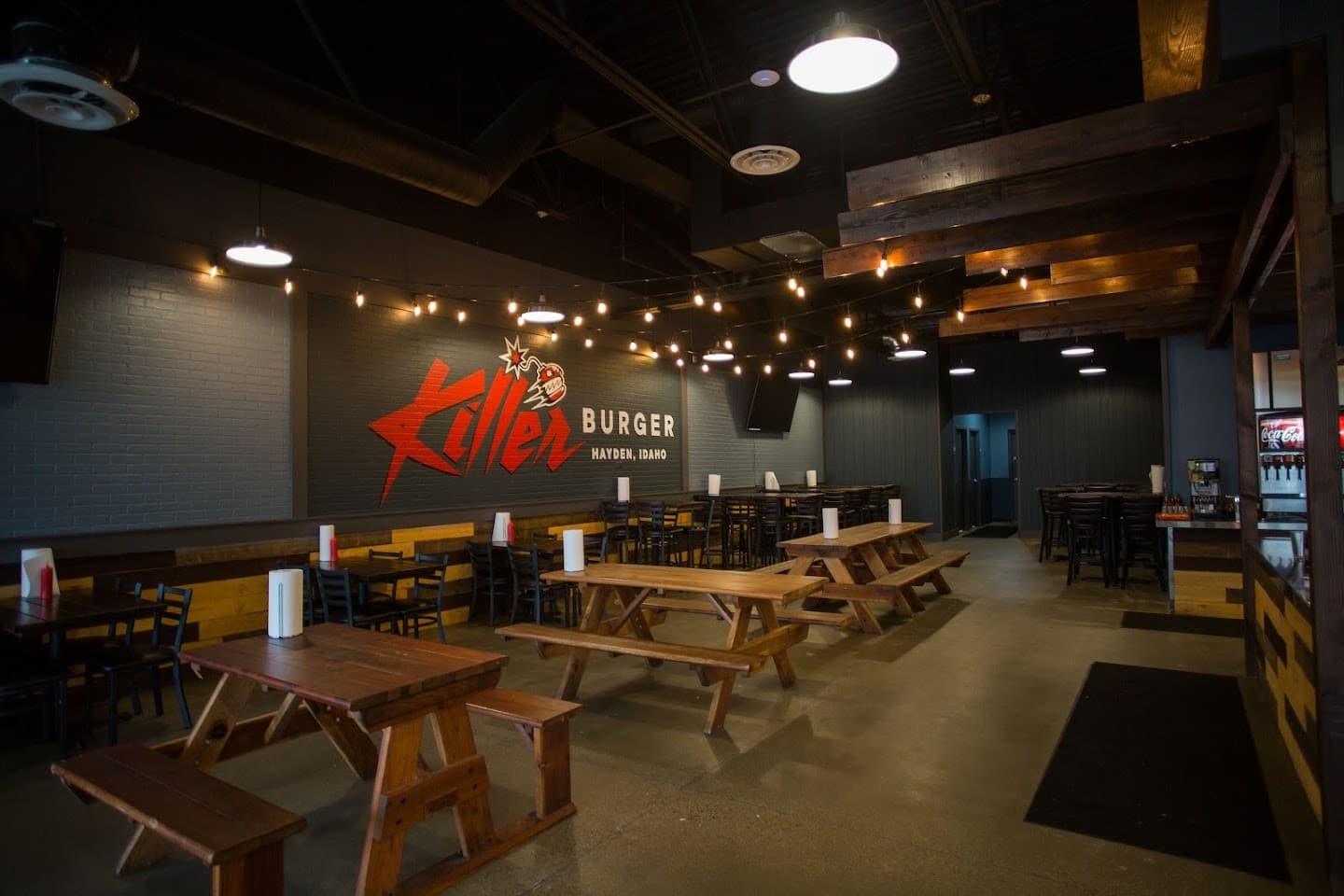 Killer Burger Hayden — interior dining room with picnic tables and string lights