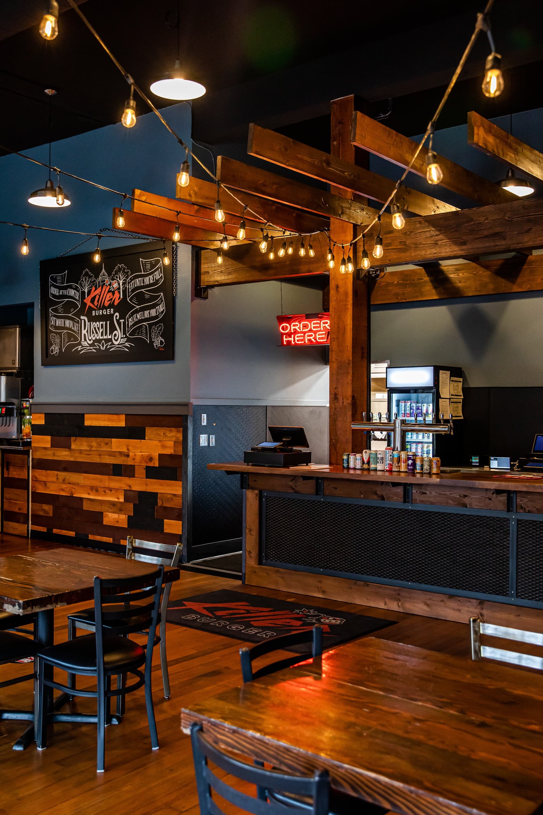 Killer Burger Russell — interior order counter with exposed beams and string lights
